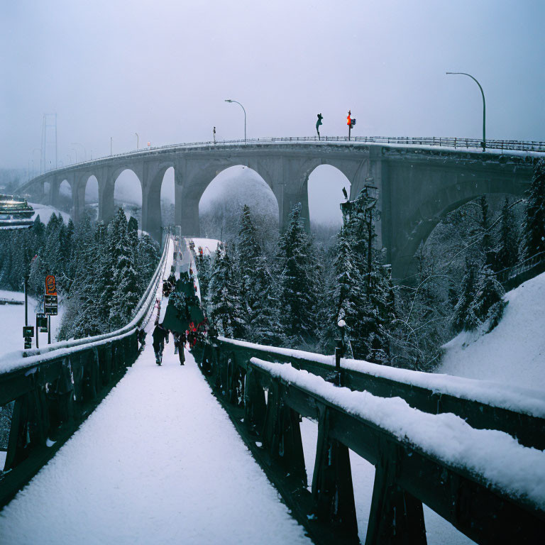 Snow-covered bridge with pedestrians, trees, arch, and traffic light under hazy sky
