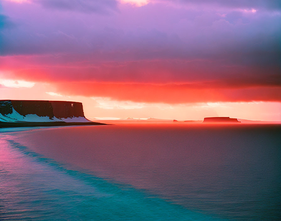 Colorful sunset over calm sea with silhouetted cliffs