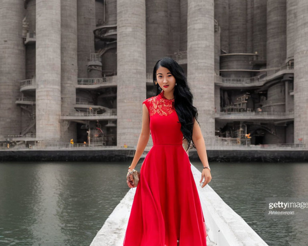 Woman in Red Dress on White Walkway by Water with Cylindrical Structures