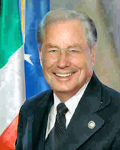 Smiling man in dark suit with flag background portrait