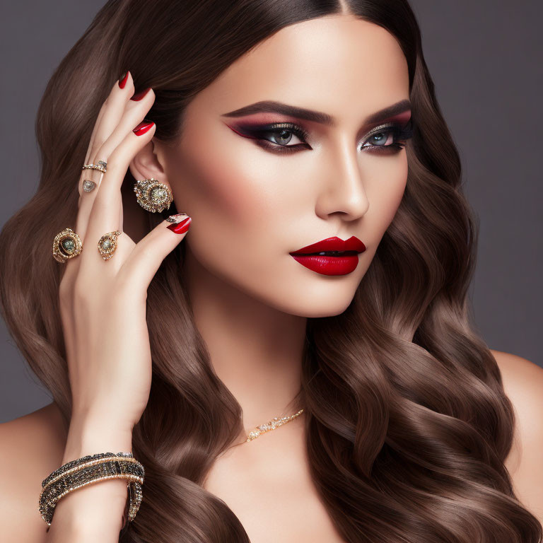 Elegant woman with bold makeup and jewelry against gray backdrop