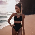 Woman in Black Swimsuit and Gold Jewelry Poses on Beach at Sunset