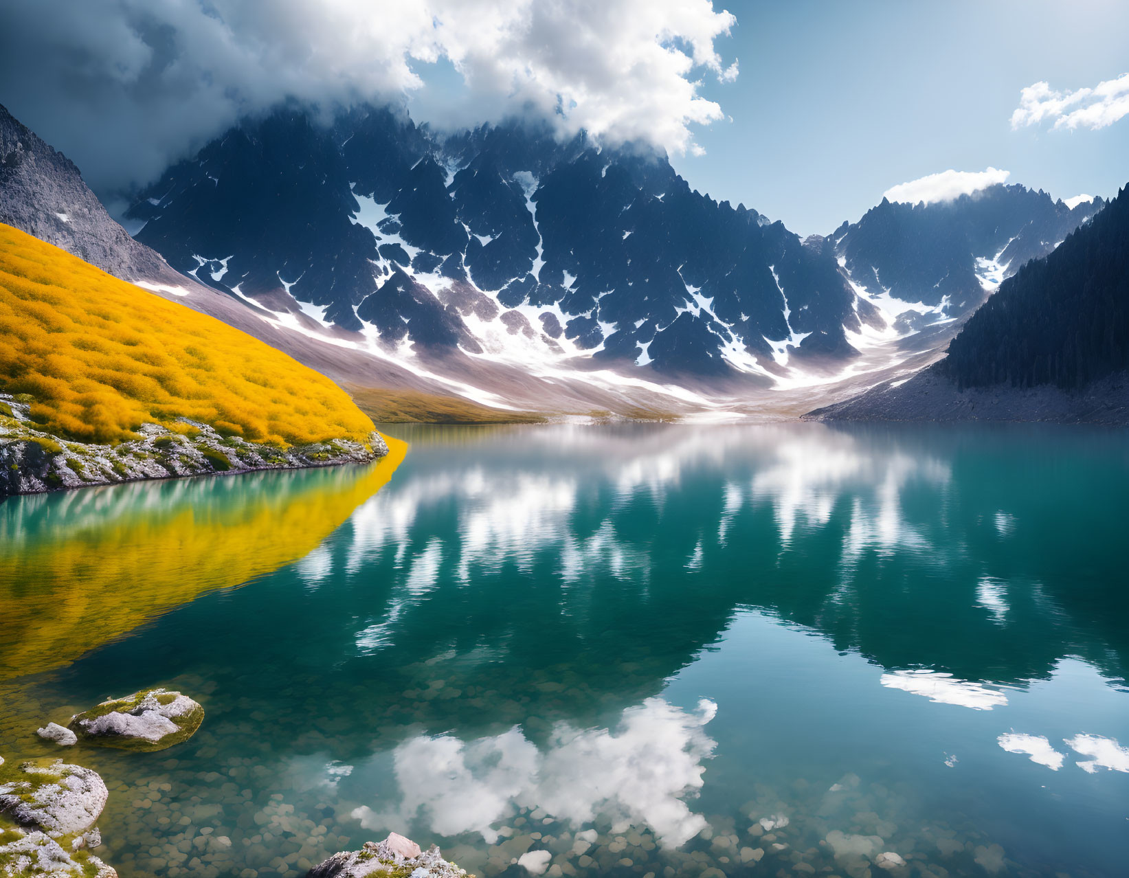 Tranquil mountain lake with snow-capped peaks and yellow hillside