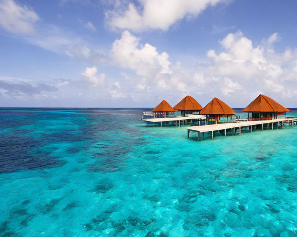 Thatched roof overwater bungalows on turquoise sea