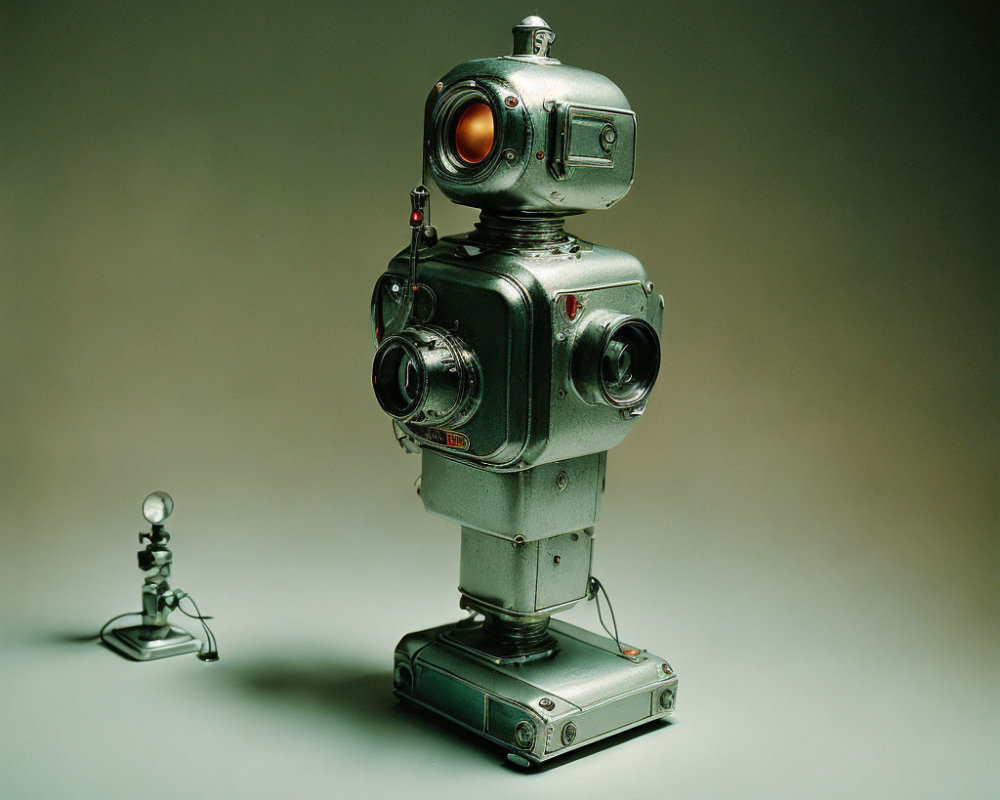 Vintage-Style Robot Made from Camera Parts with Red Eye Beside Miniature Figure