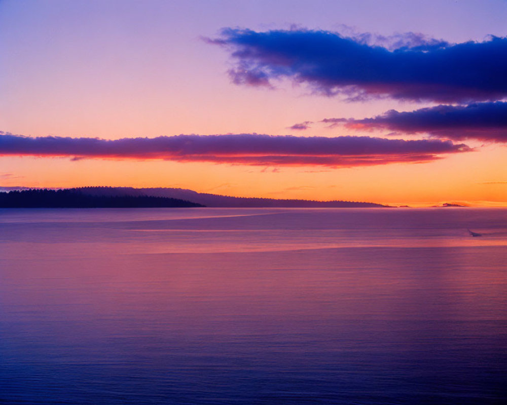 Tranquil sunset with purple and orange hues over ocean and island