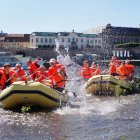 Group of People White Water Rafting with Historical Buildings
