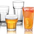 Four ornate glass tumblers with floral design, sizes vary, two clear and two filled with amber
