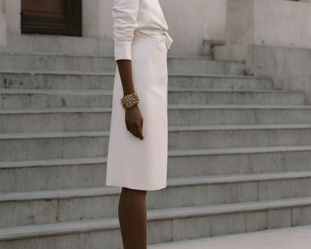Fashion model in white dress with cinched waist and afro hairstyle poses on steps