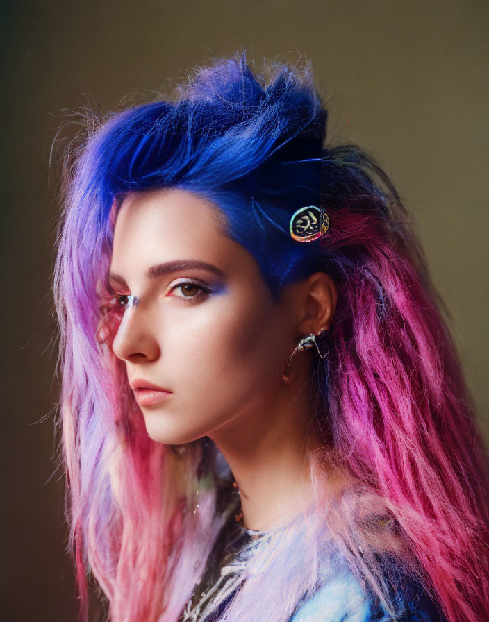 Portrait of a person with vibrant blue and pink hair and unique circular earring