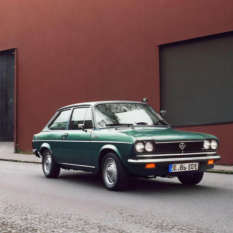Vintage Green Opel Car Parked on Street with Red Wall and Dark Grey Garage Door