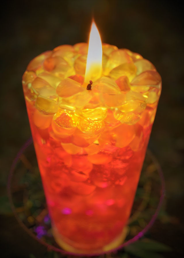 Glass Ice Candle Emitting Warm Orange Glow on Dark Background