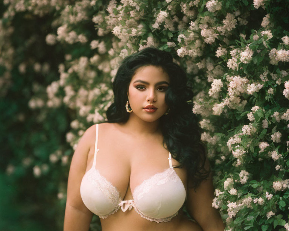 Woman in White Lingerie Posing in Lush Bushes with Pale Pink Flowers