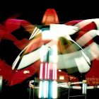 Colorful fairground ride light trails in night sky with blurred figures