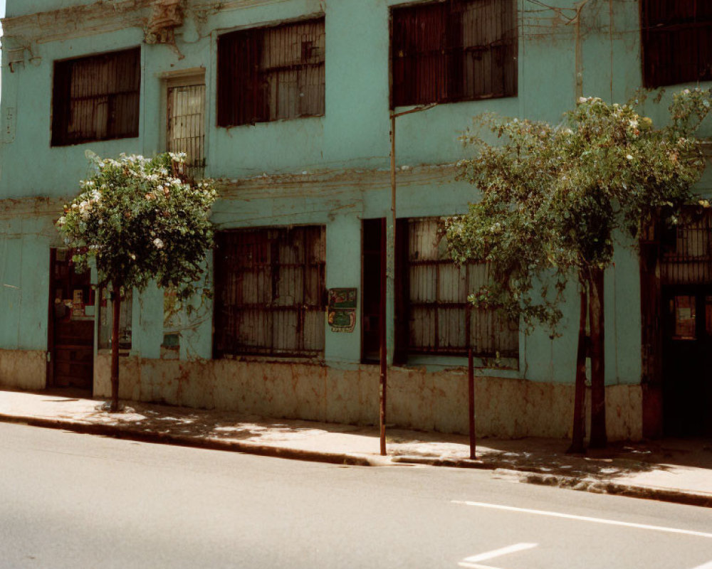 Two-story blue building with barred windows on sunny street
