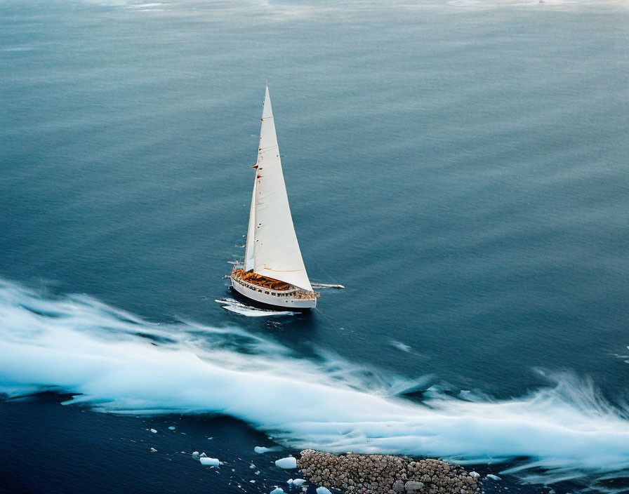 White Sailboat Sailing Near Rocky Coastline