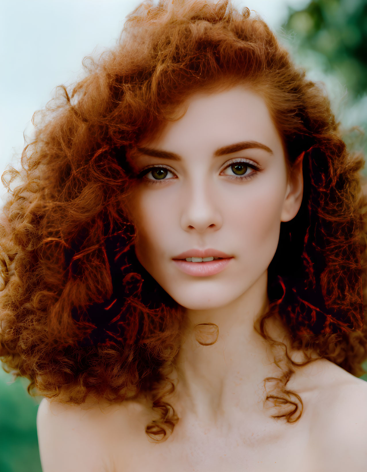 Portrait of Woman with Voluminous Curly Red Hair on Soft Green Background