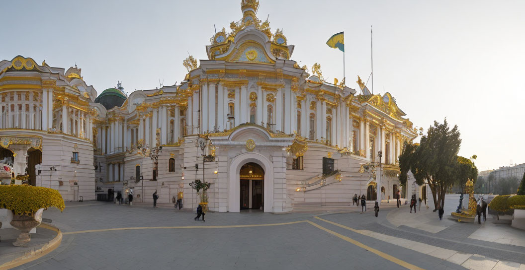 Grand ornate building with golden and white facade and Ukrainian flag at half-mast.