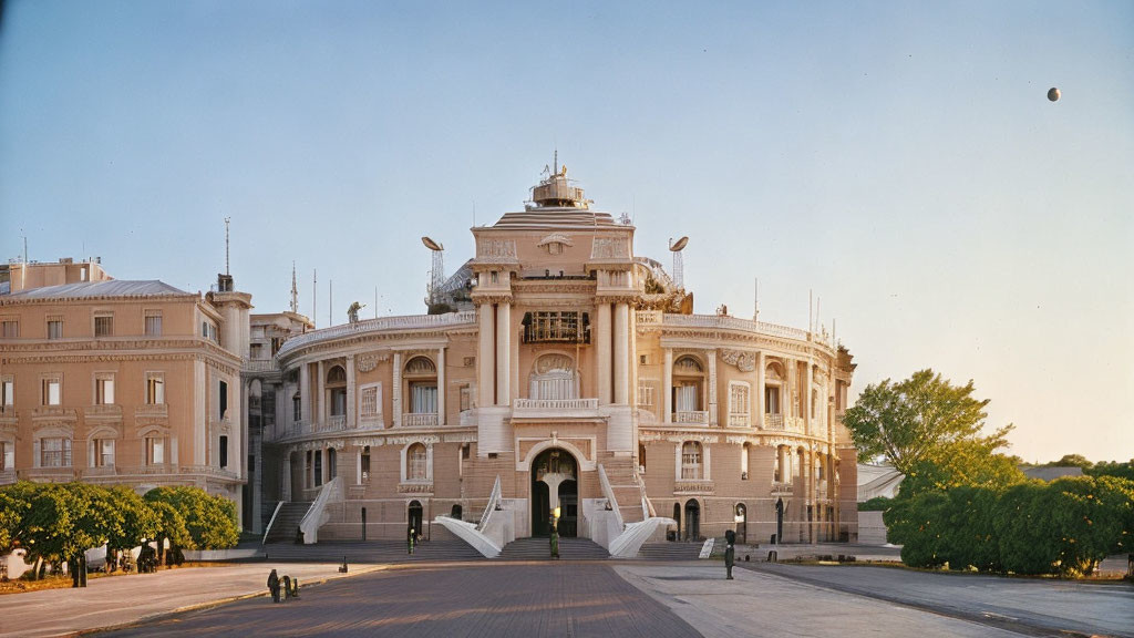 Neoclassical building with grand staircase and statues at dusk