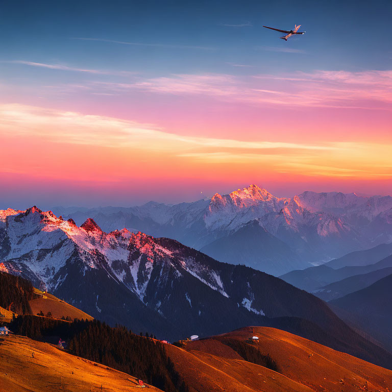 Airplane flying at sunset over snow-capped mountains and rolling hills