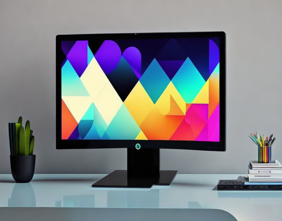 Colorful geometric wallpaper displayed on sleek monitor with desk accessories