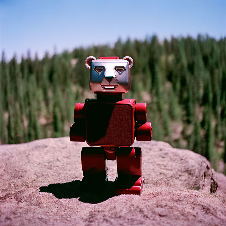 Red and Silver Bear-Shaped Robot Toy on Rock in Forest Scene