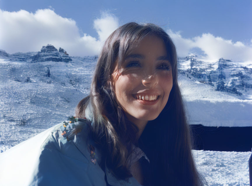 Smiling woman with long hair in snowy mountains landscape