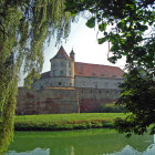 Digital artwork of grand castle in lush greenery by calm waters