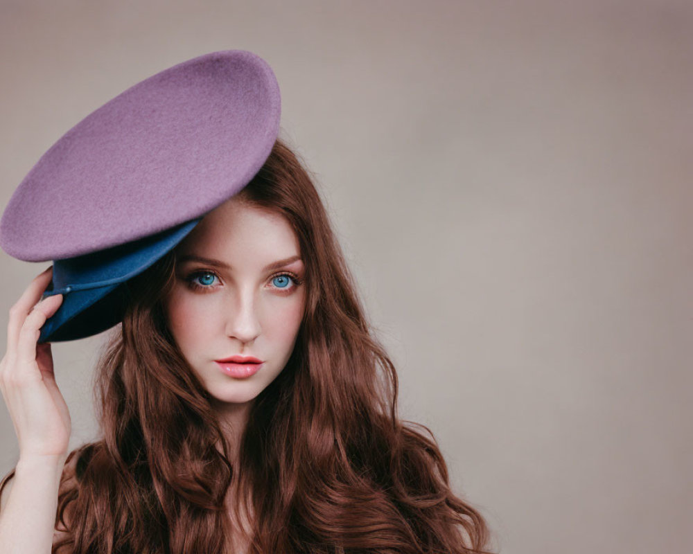 Young woman with blue eyes and brown hair holding a purple hat
