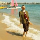 Surreal image of man with exaggerated smile on beach.