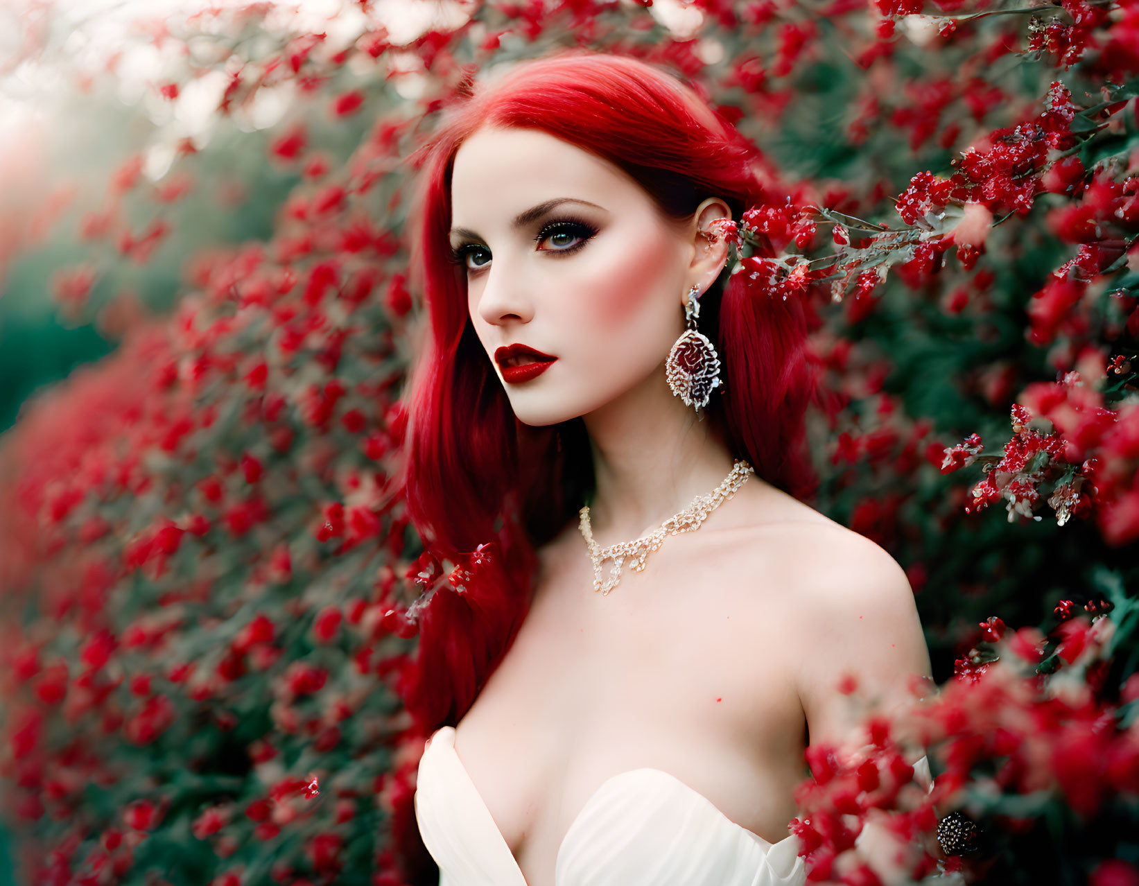 Striking red-haired woman in white dress among vibrant red blossoms