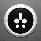 Silver-framed round button with black center and exclamation mark connected to dots