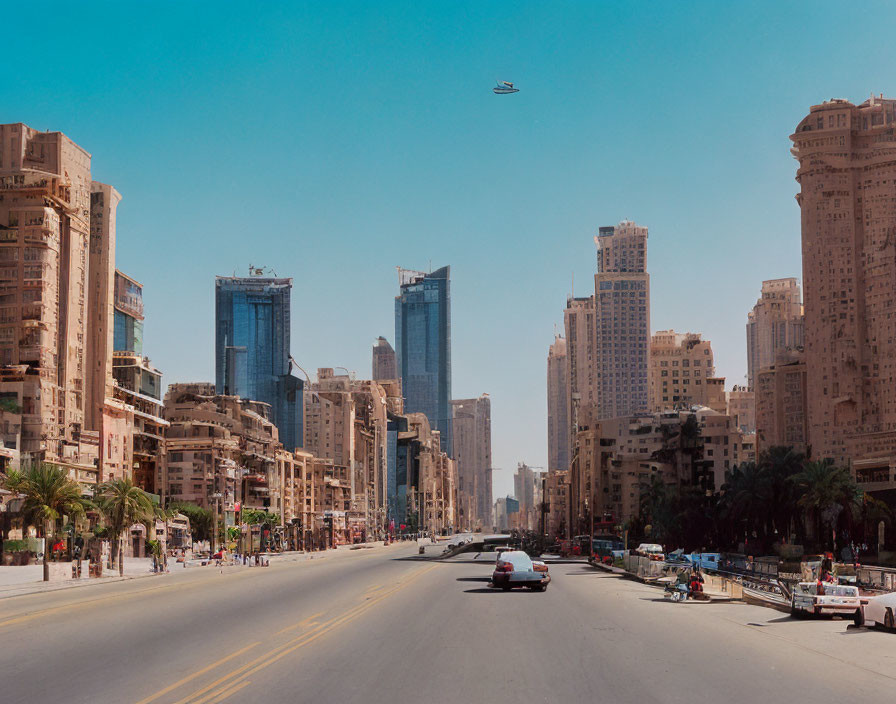 Urban street with tall buildings under construction and helicopter in blue sky