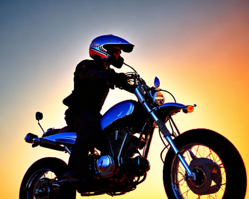 Motorcyclist silhouette against vibrant sunset sky