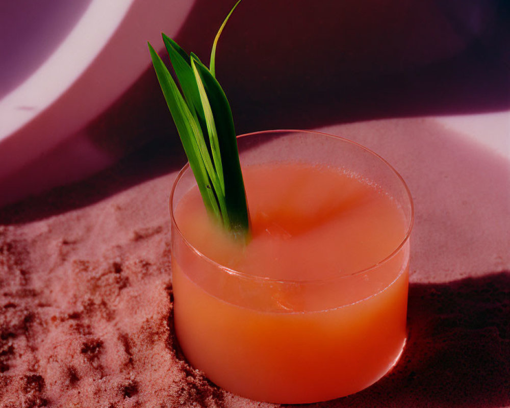 Tropical cocktail with green garnish on sand under palm leaf shadow