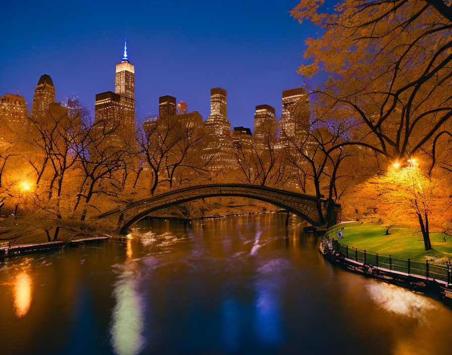 Tranquil night scene of reflective river and stone bridge in Central Park