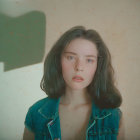 Young woman in denim jacket with medium-length hair gazing ahead under speckled pattern