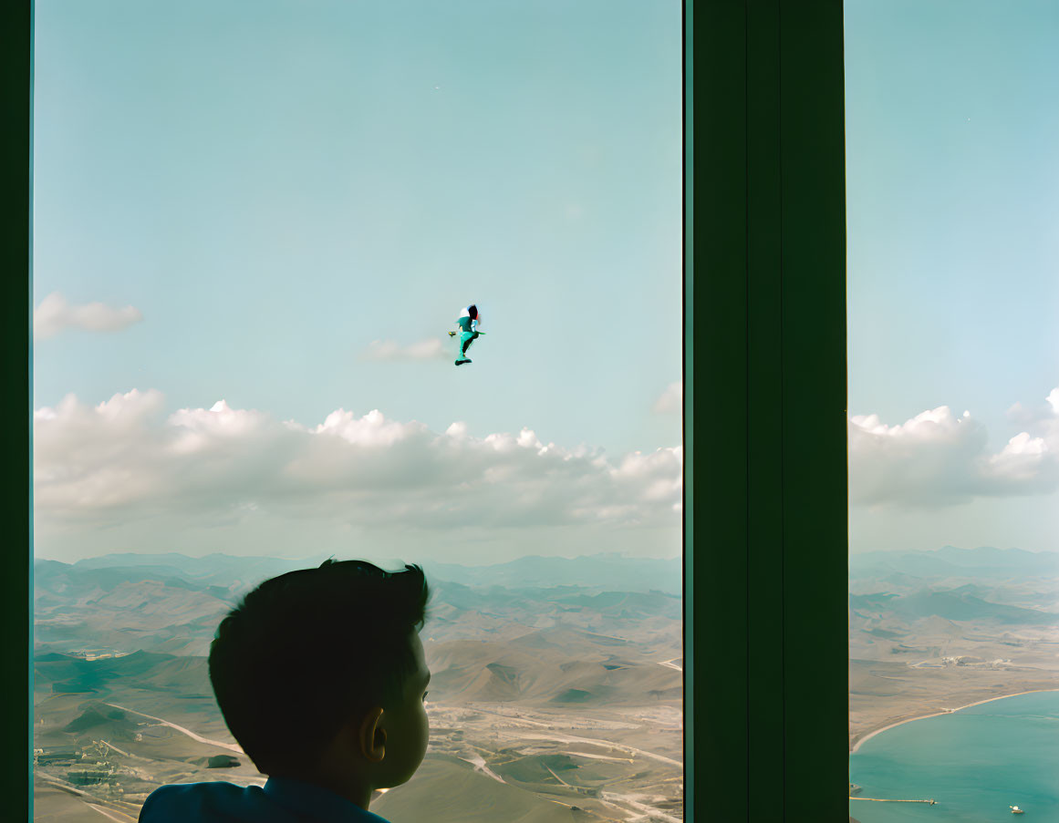 Child watching skydiver over scenic landscape