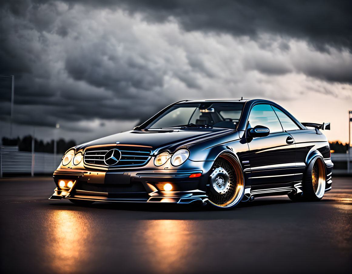 Black Mercedes-Benz CLK with Aftermarket Modifications and Chrome Wheels Parked on Empty Asphalt Lot Under Dramatic