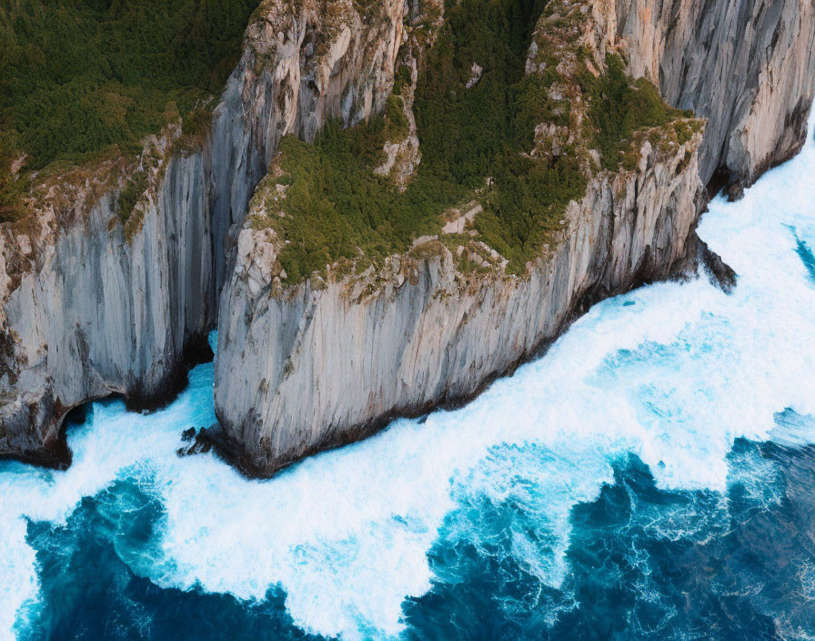 Aerial View of Rugged Cliffs Meeting Ocean Waves