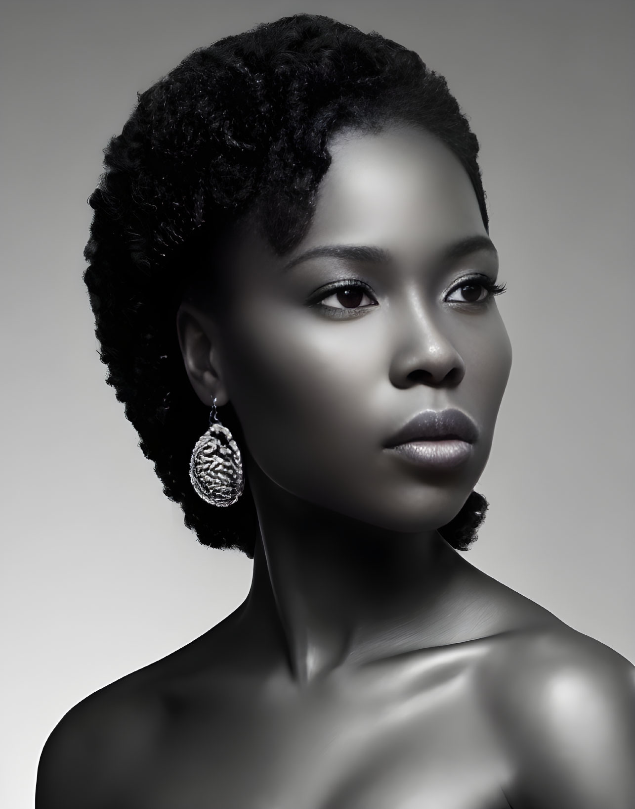 Grayscale portrait of a woman with elegant earrings and styled natural hair.