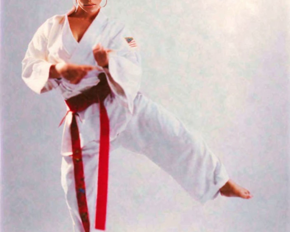 Karate practitioner in red and black belt performing high kick pose.