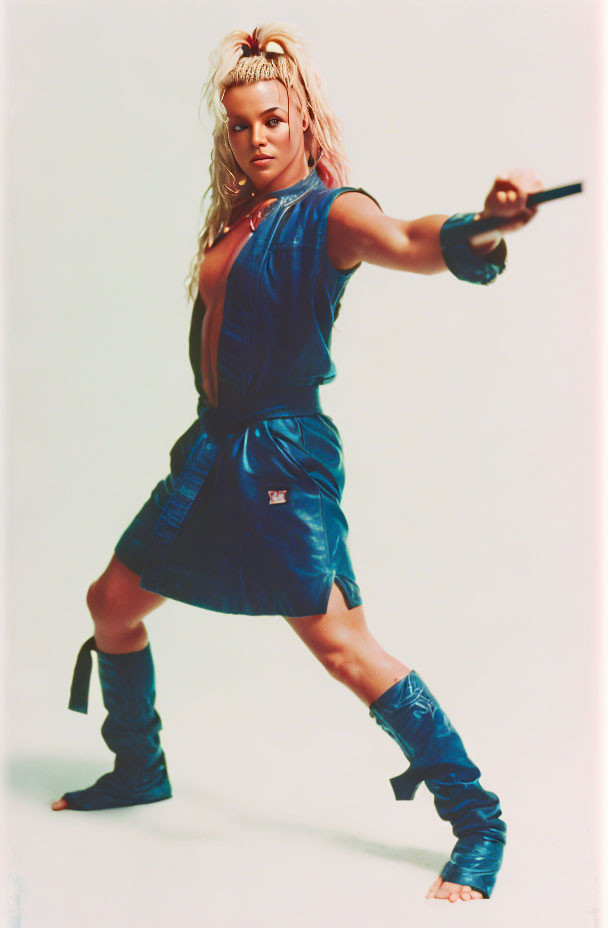 Dynamic Woman in Blue Outfit Poses with Martial Arts Weapon