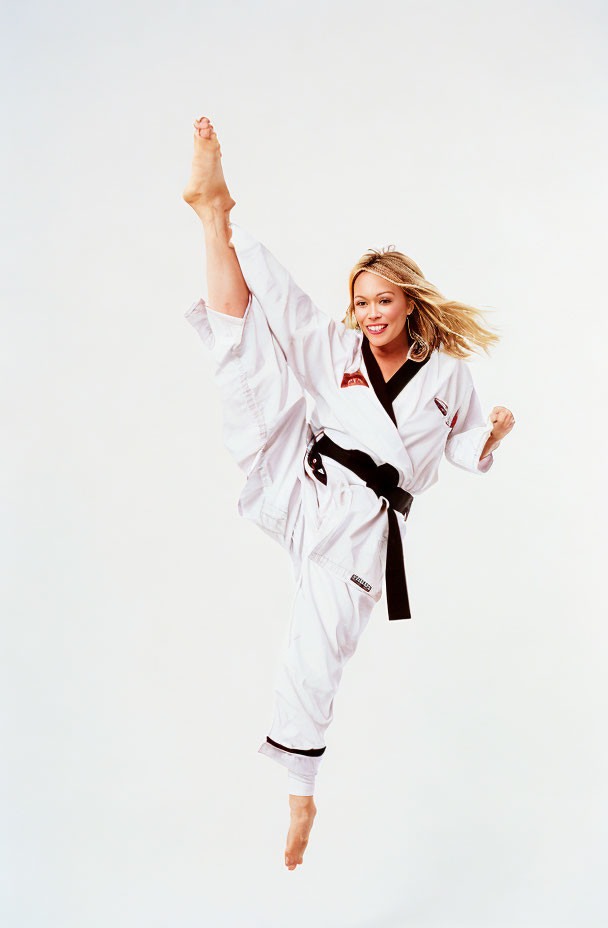 Martial artist in white taekwondo uniform with black belt executing high kick