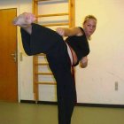 Martial artist in black attire practicing high kick with superimposed face