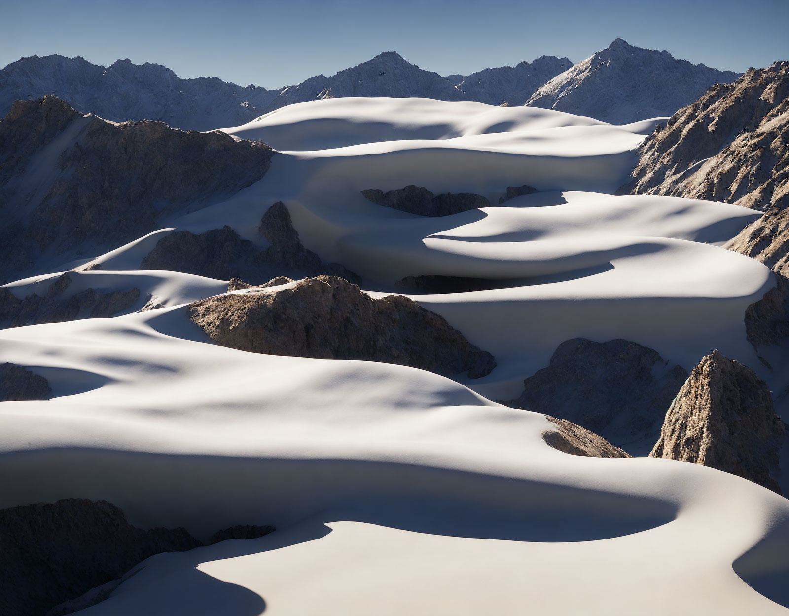 Snow-covered sand dunes against rugged mountain backdrop