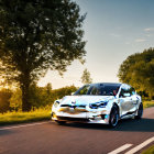 White Electric Car Speeding on Scenic Road with Trees and Sunlight