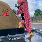 Pink furry costume person with bird-like face and white object near gold U-2 structure