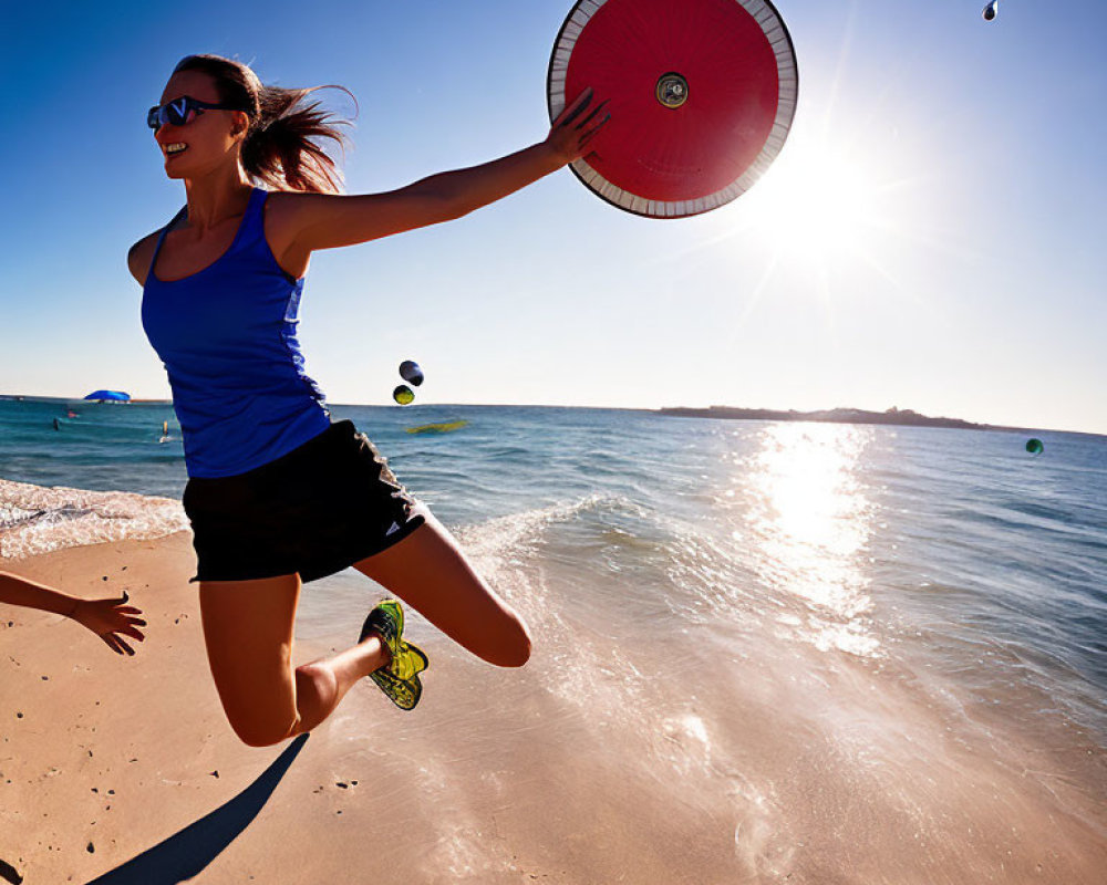 Woman in sportswear playing frisbee on sunny beach