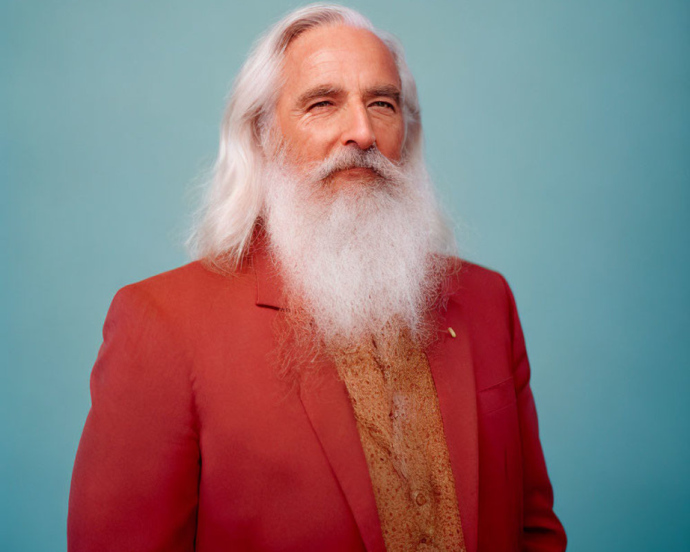 Elderly man with long white beard smiling in red suit on blue background